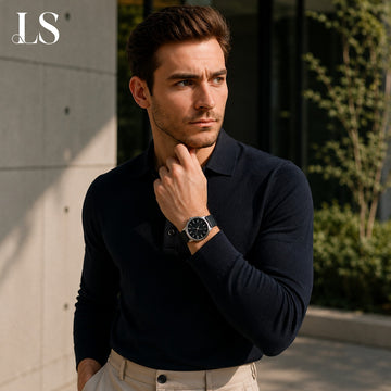 Man in a navy knit polo beside a planted wall